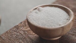 a wooden bowl filled with sugar on top of a wooden table kecoa
