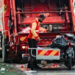 A sanitation worker managing waste disposal behind a garbage truck in Klang, Selangor. sanitasi